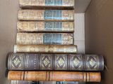 several books are stacked in a cardboard box on top of each other