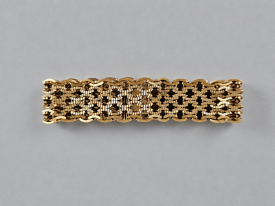 gros plan d'un bracelet en or sur une surface grise