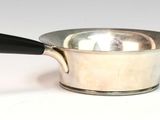 a silver saucepan with a black handle on a white surface