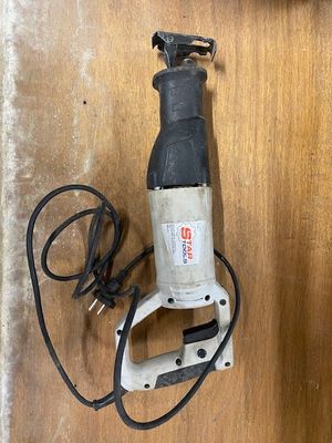 an image of a corded electric drill sitting on top of a wooden table