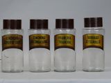 three glass jars with brown lids are lined up on a white surface
