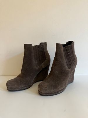 une paire de bottines en daim marron posées sur une surface blanche
