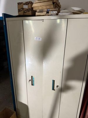 une armoire métallique surmontée d'une horloge, dans une pièce