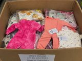 une boîte en carton remplie de vêtements pour bébés, mise en vente dans la rue