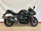 a picture of a black and green motorcycle parked in front of a white backdrop