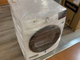 Des cartons contenant des lave-linge et des sèche-linge sont empilés par terre dans un magasin.