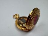 a close up of a gold pocket watch on a white surface