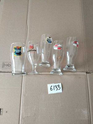 quatre verres à bière vides posés sur une boîte en carton