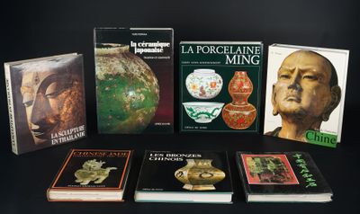 Plusieurs livres sont posés sur une surface noire, sur fond noir.