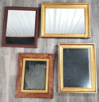 quatre miroirs encadrés sont posés les uns à côté des autres sur un plancher en bois