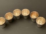 six silver cups are lined up in a circle on a table