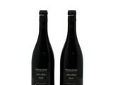 two bottles of wine sitting next to each other on a white surface