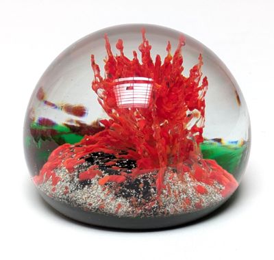 une boule de verre contenant une flamme, posée sur une surface blanche