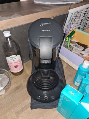 une cafetière noire posée sur un plan de travail, à côté d'une bouteille d'eau
