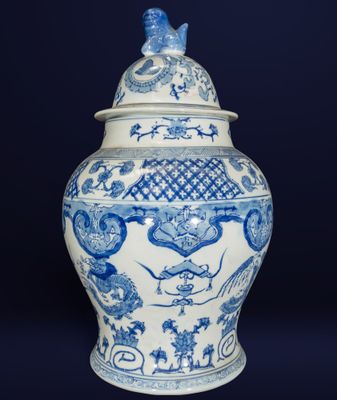 vase bleu et blanc surmonté d'un oiseau, sur fond noir