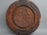 an old wooden plate with a picture of a ship on it