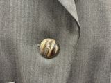 bouton sur une veste grise orné d'un bouton rayé