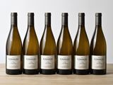six bouteilles de vin blanc alignées sur une table en bois