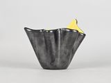 a close up of a black vase with a yellow top