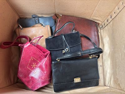 de nombreux sacs de toutes sortes dans une boîte en carton posée par terre