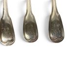three silver spoons are lined up in a row on a white surface
