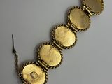 a close up of a gold bracelet on a white surface