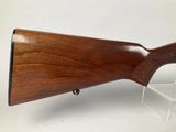 a rifle with a wooden barrel on a clear stand