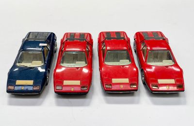 quatre petites voitures sont alignées sur une surface blanche
