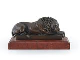 une statue en bronze représentant un lion, posée sur un socle en marbre rouge