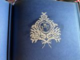 an open blue book with a gold embroidered design on it