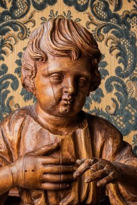 statue en bois représentant un jeune garçon tenant un oiseau dans ses mains