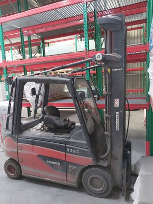 a red fork truck parked in a warehouse next to a stack of pallets