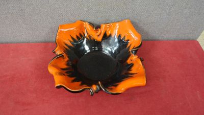 an orange and black flower shaped bowl on a red surface