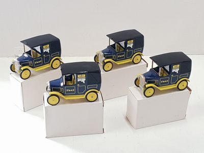 quatre petites voitures jouets bleues et jaunes posées sur des boîtes blanches