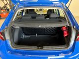 the back of a blue car with its trunk open in a garage