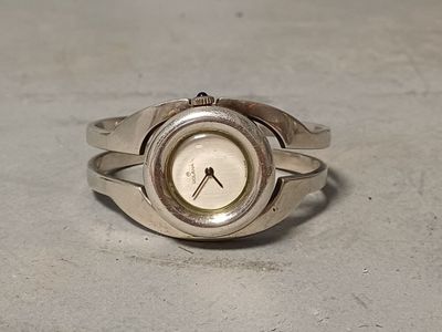 a silver ring with a clock on it on a table