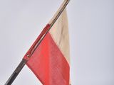 a red and white flag on a pole with a black pole