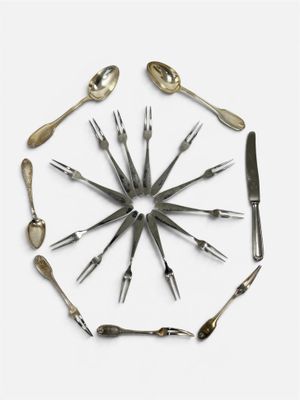 plusieurs fourchettes et cuillères disposées en cercle sur une surface blanche