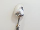 a silver spoon with a handle on a white surface