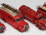 cinq camions de pompiers rouges miniatures alignés sur une surface blanche