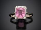 une bague sertie d'un saphir rose et de diamants, posée sur un fond noir