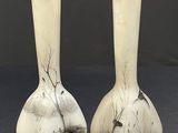 two white vases with black and white designs on them sitting on a table