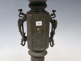 un vase antique en bronze posé sur un socle et orné de deux oiseaux