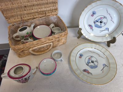 un panier en osier posé sur la table, contenant des assiettes et des tasses