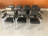 six fauteuils en cuir noir aux pieds chromés dans une pièce