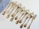 a lot of silver spoons and forks sitting on a table
