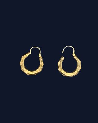a pair of gold hoop earrings on a black background