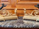 two statues sitting on a marble table with a clock in the background
