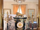 an image of a clock in a room with a chandelier in the background