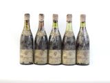six bouteilles de vin sont alignées sur une surface blanche